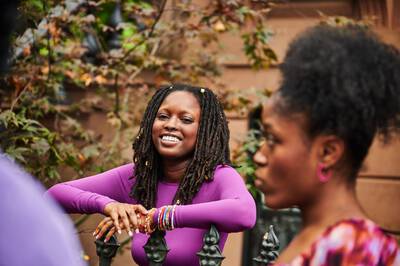 Woman in a bright purple shirt with locs